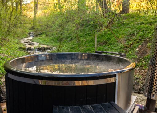 Hot tub surrounded by greenery and a creek